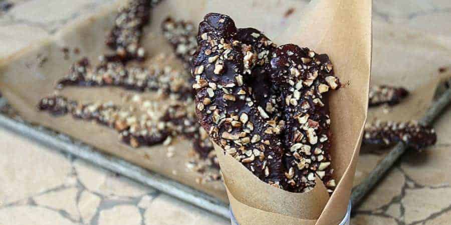 Chocolate covered maple pecan bacon strips in a cup.