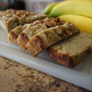 Keto banana bread slices on cutting board next to whole bananas.