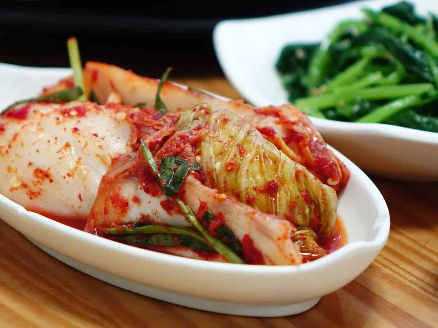 Fermented foods: Kimchi in a dish on table next to dish of green beans.