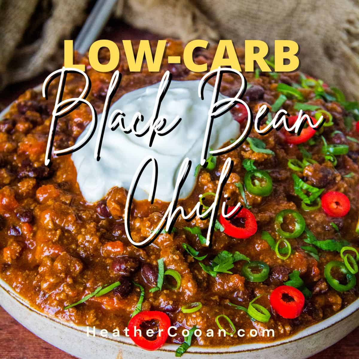 Bowl of Black Bean Chili Topped with Sour Cream, Red and Green Jalapeno Slices, Cilantro, and a Lime Wedge.
