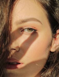 woman shielding her eyes from the sun, shadow of hand on her face - The Power of Antioxidants for Staying Young