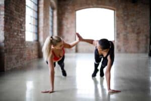 Young women high fiving at the gym - How to Stay Motivated to Exercise