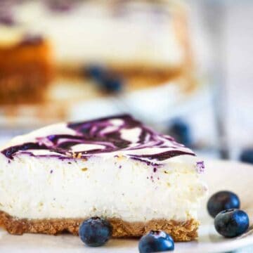 Blueberry Swirl Cheesecake Slice on a plate with fresh blueberries