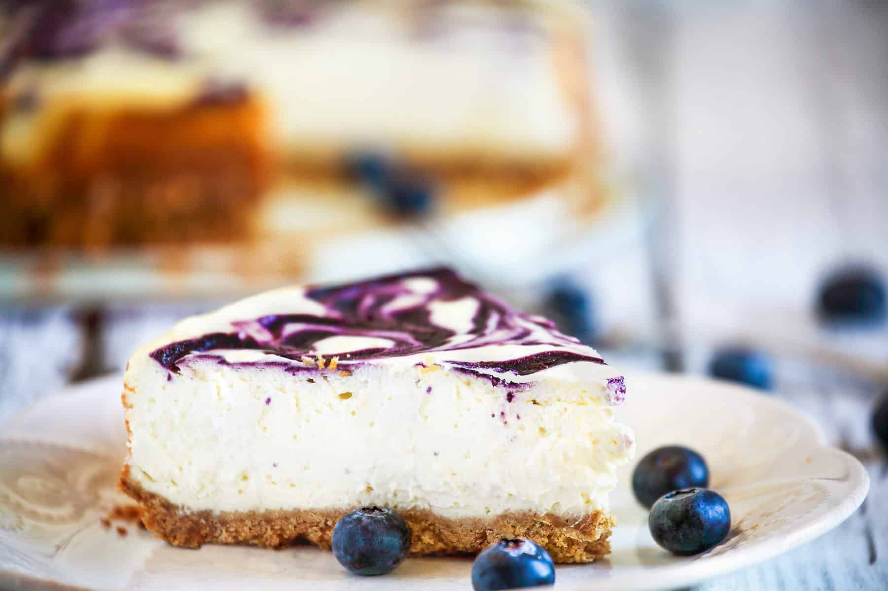 Blueberry Swirl Cheesecake Slice on a plate with fresh blueberries